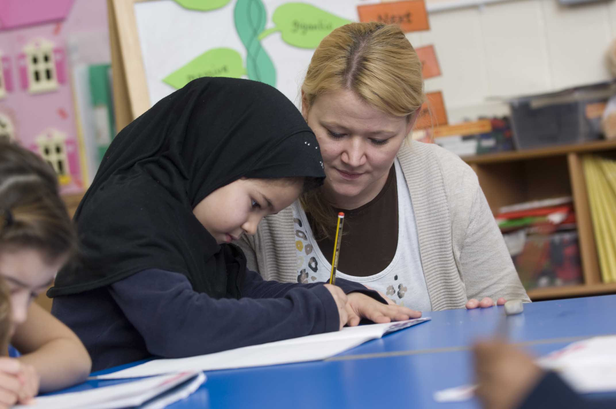Child writing with support from an adult